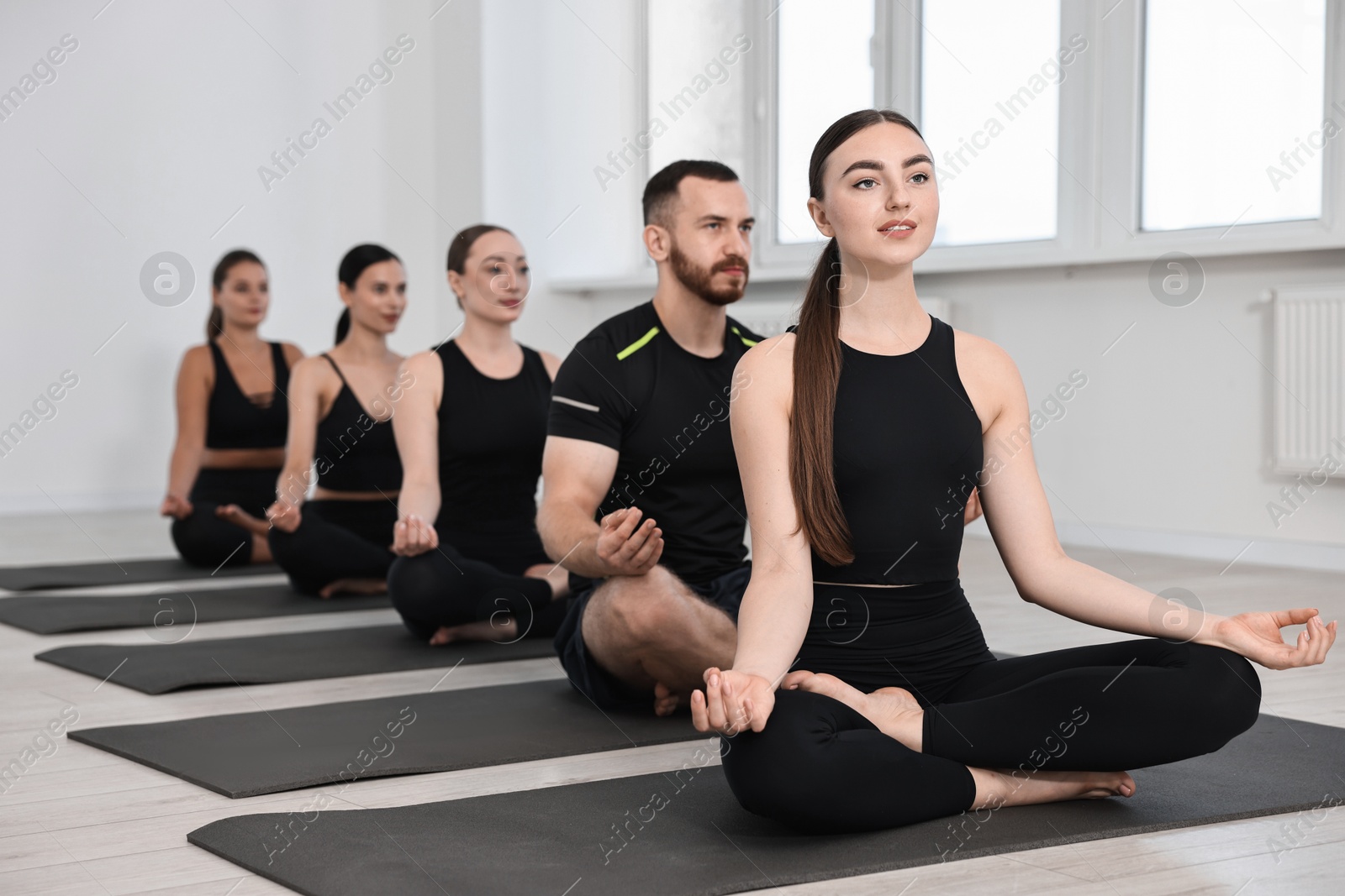 Photo of Group of people meditating on mats in yoga class