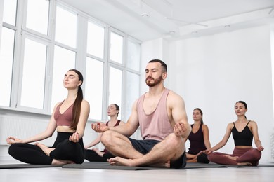 Photo of Group of people meditating on mats in yoga class