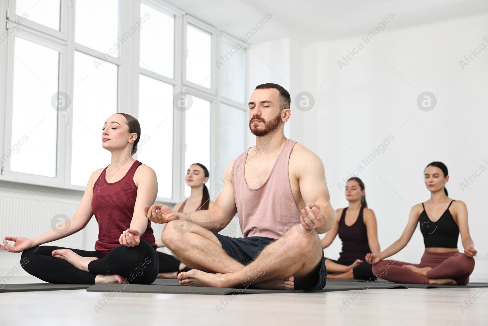 Photo of Group of people meditating on mats in yoga class