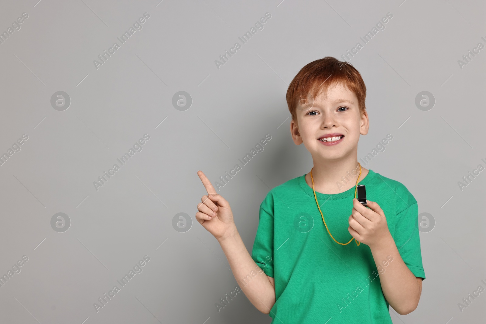 Photo of Little boy with whistle on grey background, space for text