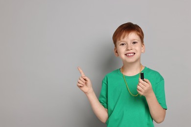 Photo of Little boy with whistle on grey background, space for text