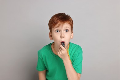 Little boy blowing whistle on grey background