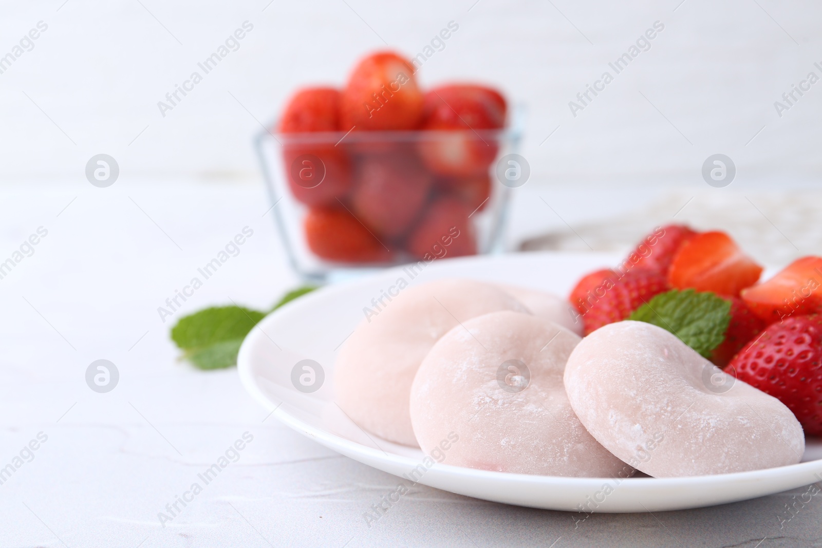 Photo of Delicious mochi and strawberries on white table, closeup