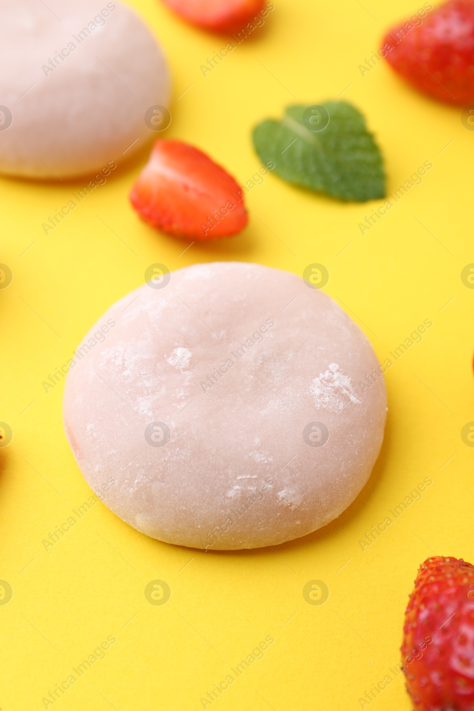 Photo of Delicious mochi and strawberries on yellow background, closeup