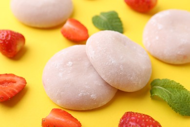 Photo of Delicious mochi and strawberries on yellow background, closeup