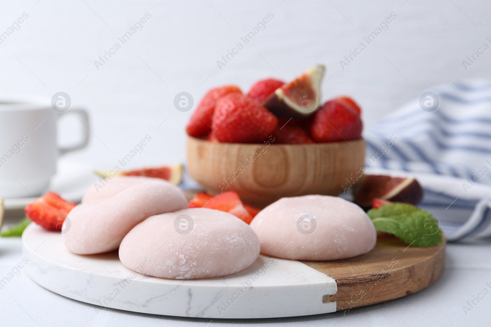 Photo of Delicious mochi, strawberries and fig on white table, closeup