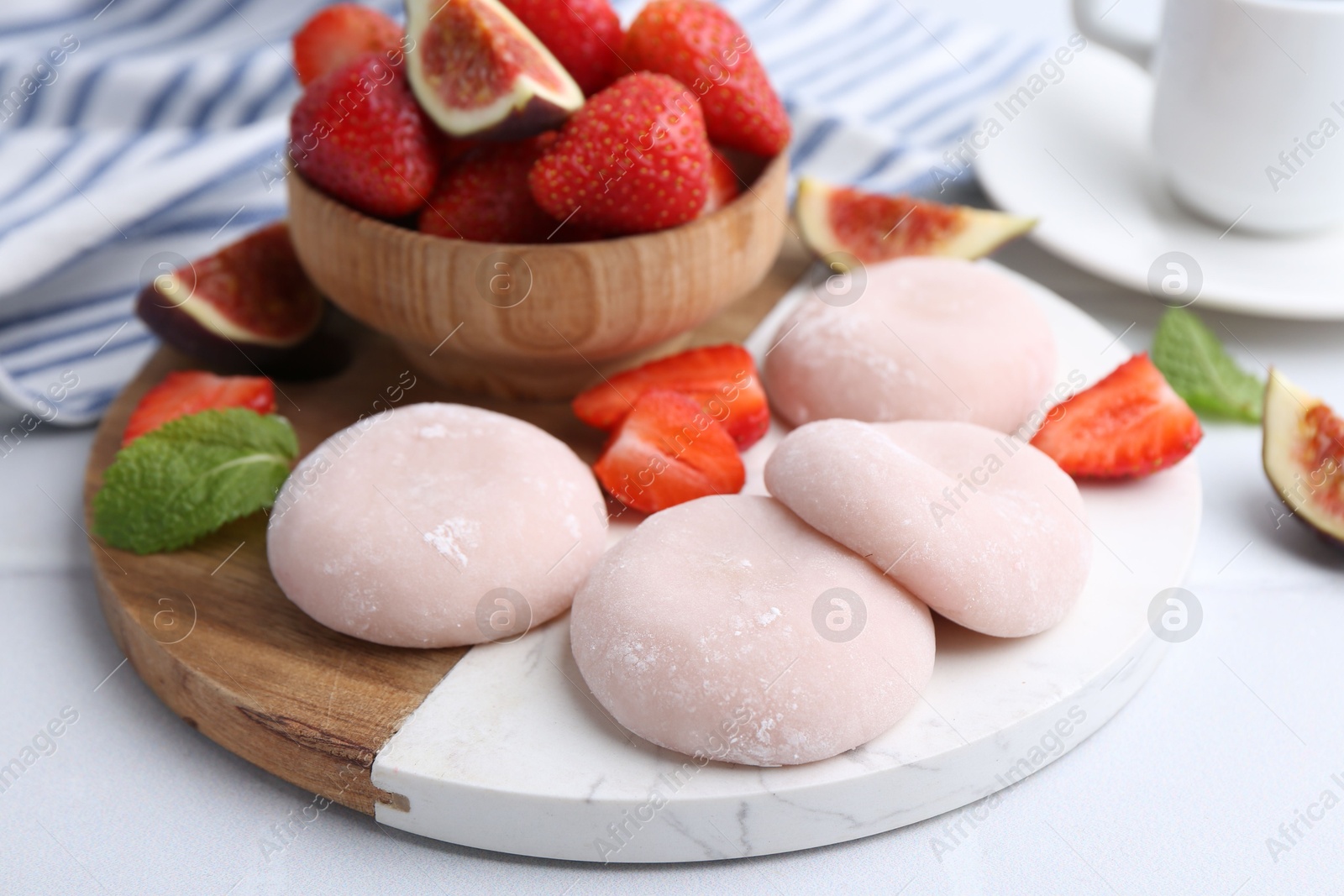 Photo of Delicious mochi, strawberries and fig on white table, closeup