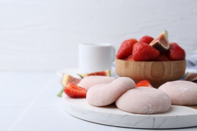 Photo of Delicious mochi, strawberries and fig on white table, closeup