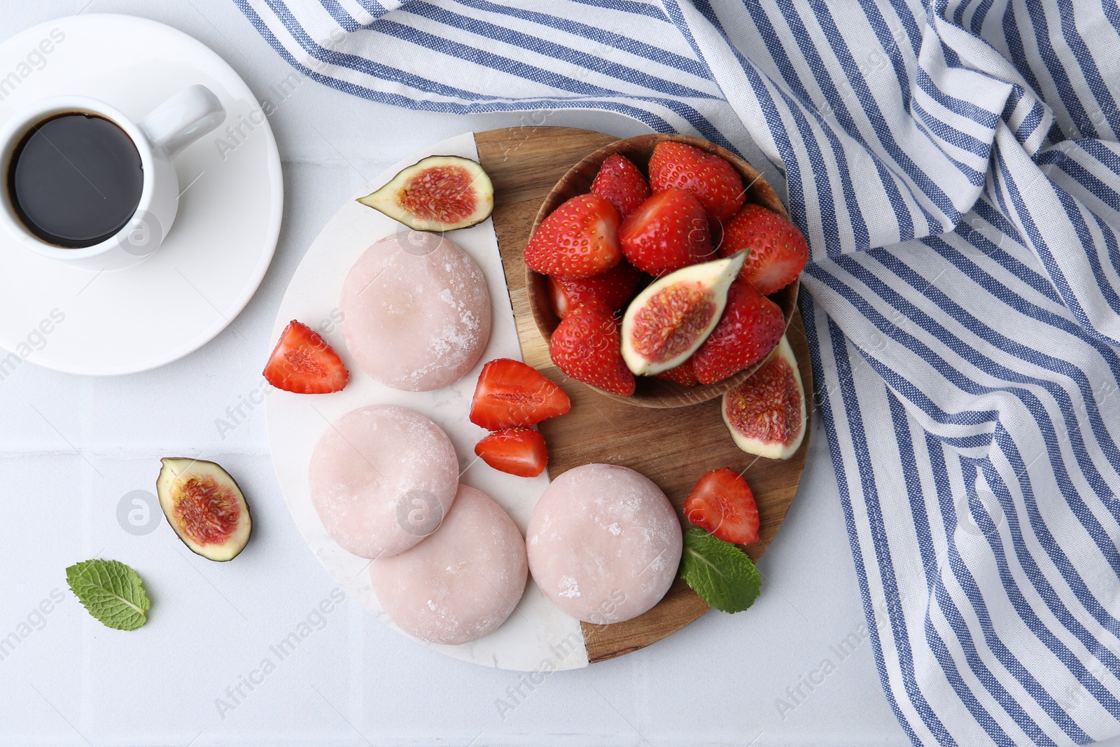 Photo of Delicious mochi, strawberries, figs and coffee on white tiled table, top view