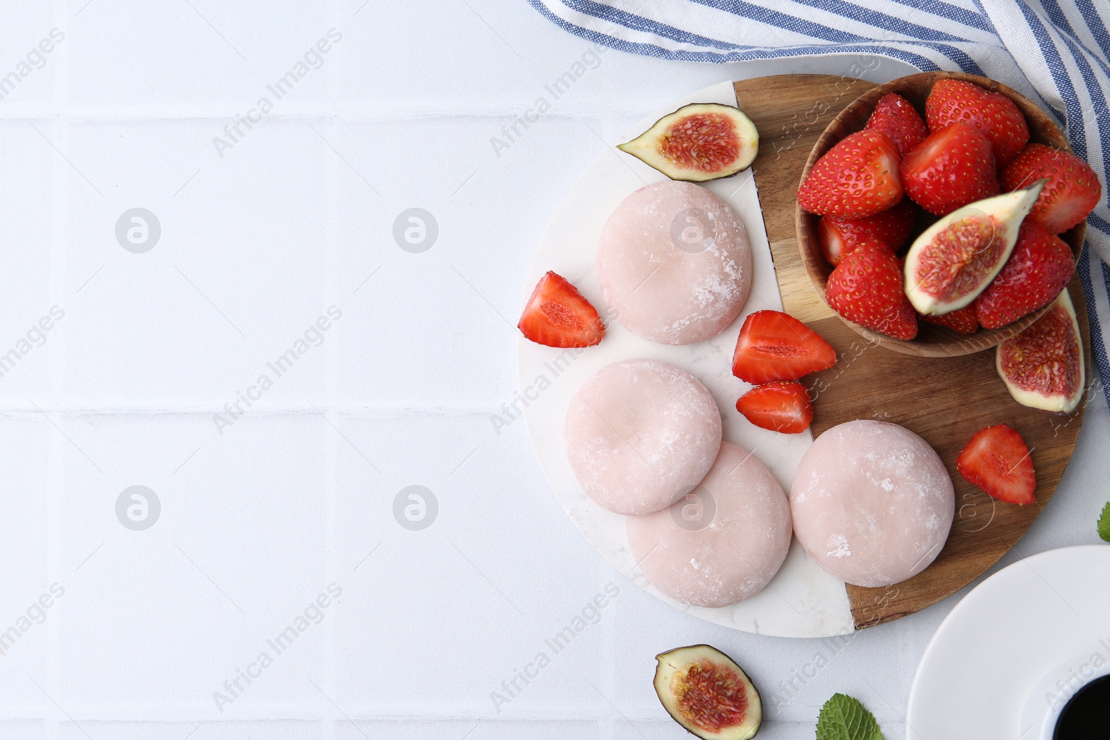 Photo of Delicious mochi, strawberries and figs on white tiled table, top view. Space for text