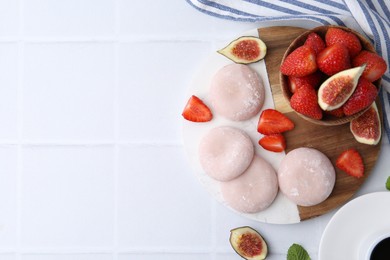 Delicious mochi, strawberries and figs on white tiled table, top view. Space for text