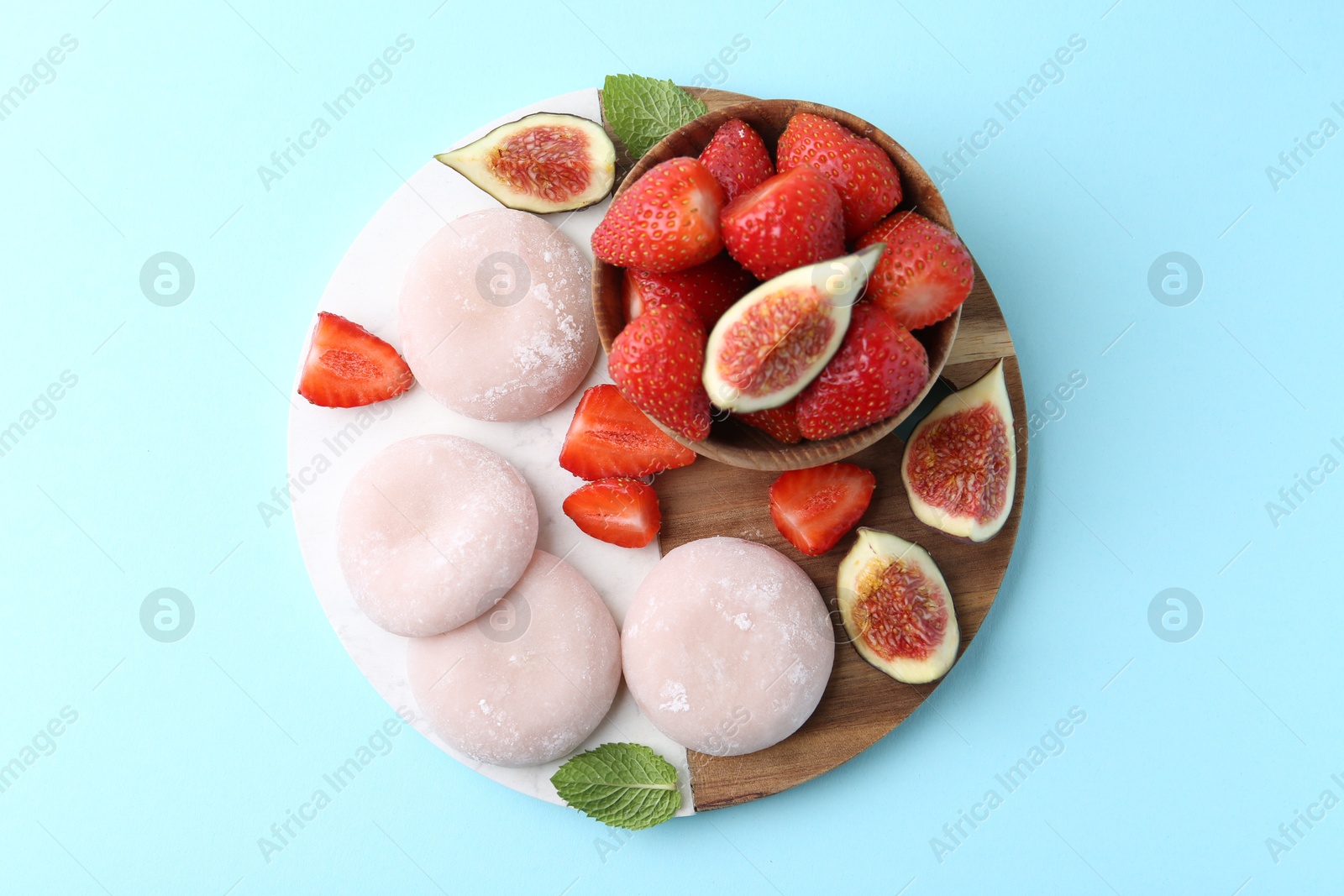 Photo of Delicious mochi, strawberries and figs on light blue background, top view