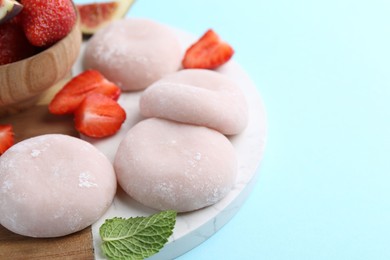 Photo of Delicious mochi and strawberries on light blue background, closeup