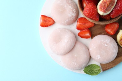 Delicious mochi, strawberries and fig on light blue background, top view