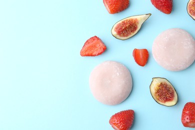 Photo of Delicious mochi, strawberries and figs on light blue background, flat lay. Space for text