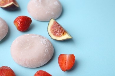 Delicious mochi, strawberries and figs on light blue background, closeup. Space for text