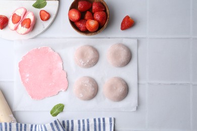 Tasty homemade mochi, dough and strawberries on white tiled table, top view