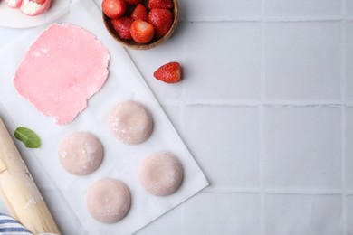 Photo of Tasty homemade mochi, dough and strawberries on white tiled table, top view. Space for text