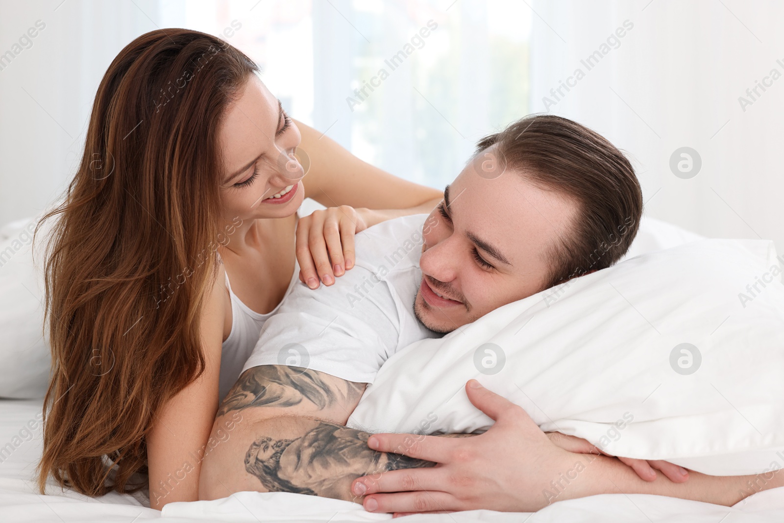 Photo of Happy couple spending time together on bed at home