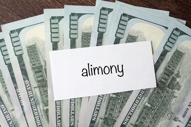 Alimony. Blank card and dollar banknotes on wooden table, top view