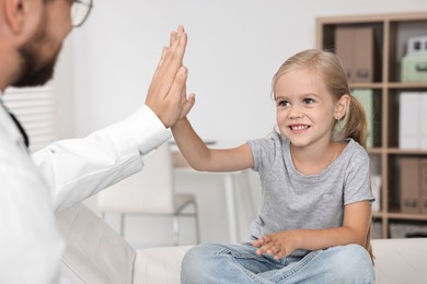 Doctor giving high five to little girl in hospital, closeup