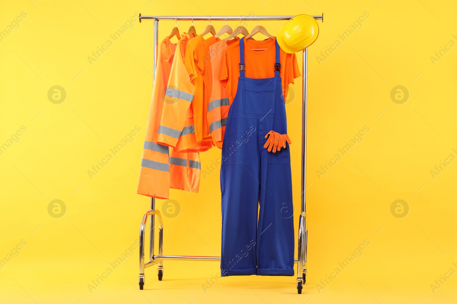 Photo of Workers' uniforms on clothing rack against yellow background