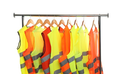 Different bright reflective vests on clothing rack isolated on white