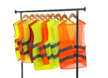 Photo of Different bright reflective vests on clothing rack isolated on white