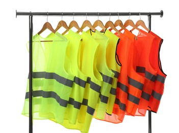 Photo of Different bright reflective vests on clothing rack isolated on white