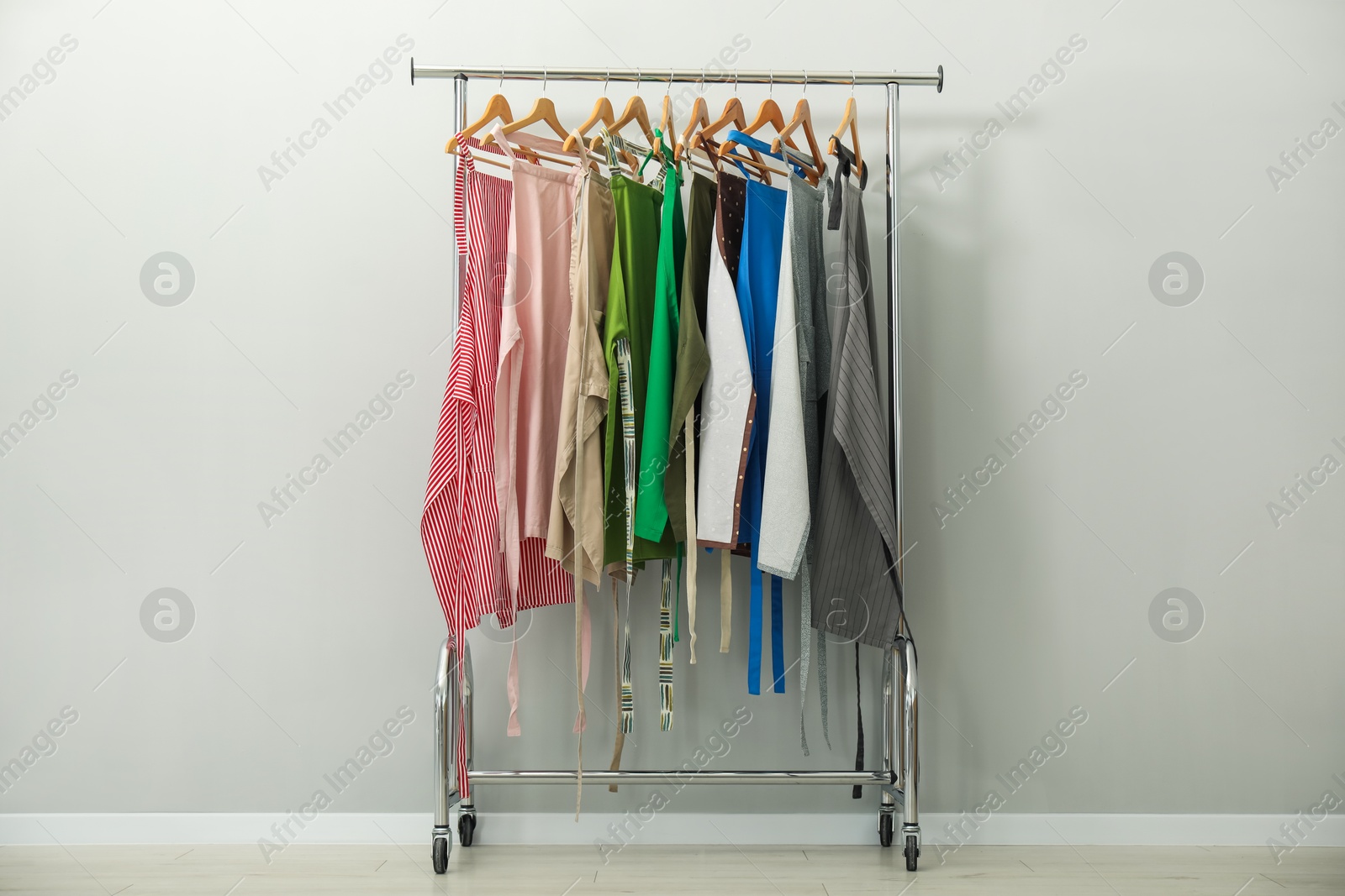 Photo of Aprons on clothing rack near light grey wall