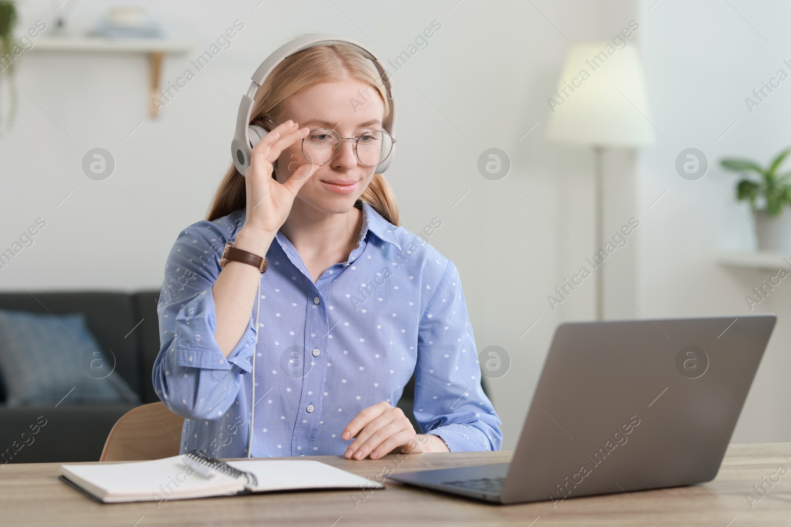 Photo of Interpreter in headphones working with laptop at table indoors