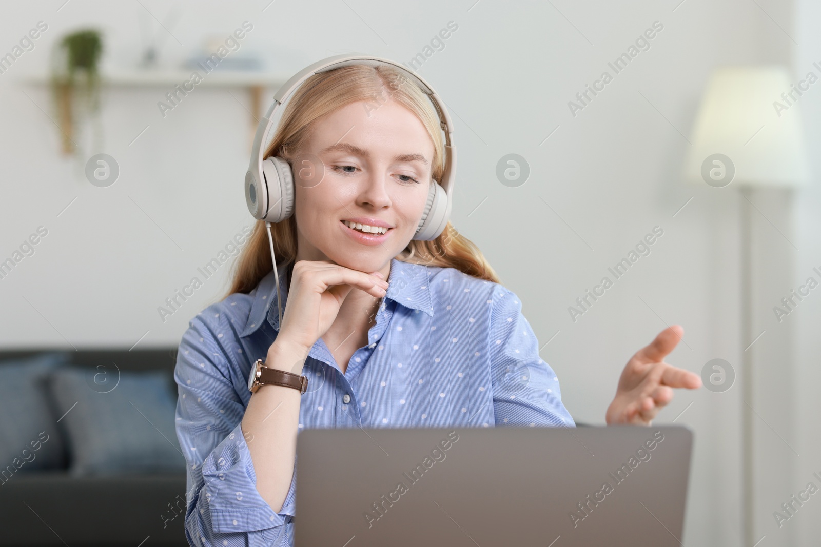 Photo of Interpreter in headphones having video chat via laptop indoors