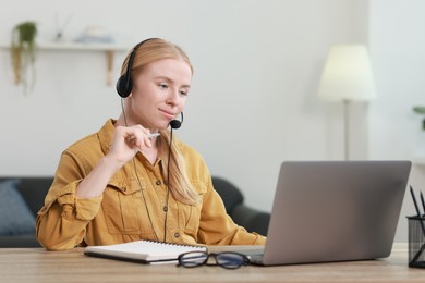 Interpreter in headset working with laptop at table indoors