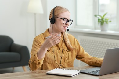 Interpreter in headset having video chat via laptop at table indoors