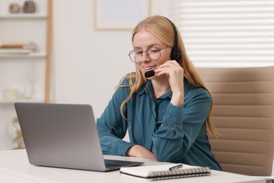 Photo of Interpreter in headset working with laptop at table indoors