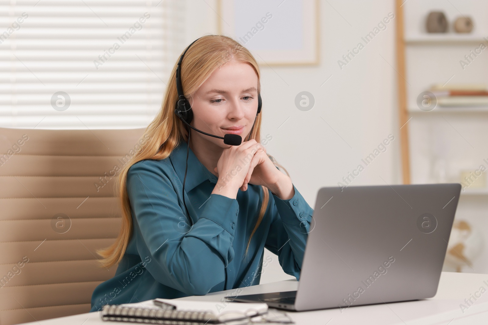 Photo of Interpreter in headset working with laptop at table indoors