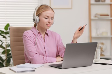 Interpreter in headphones having video chat via laptop at table indoors