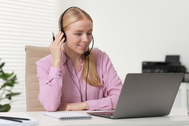 Interpreter in headset working with laptop at table indoors