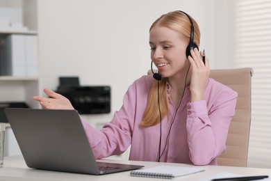 Interpreter in headset having video chat via laptop at table indoors