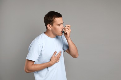 Photo of Man using asthma inhaler on grey background