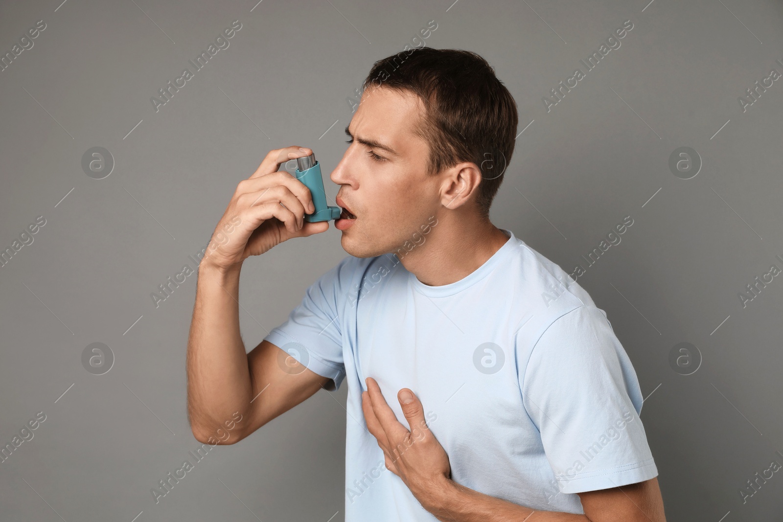 Photo of Man using asthma inhaler on grey background