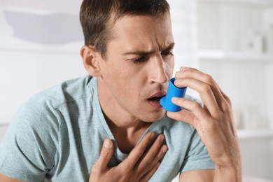 Photo of Man using inhaler at home. Asthma treatment