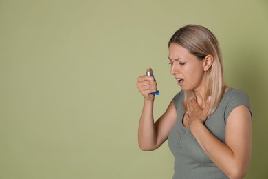 Photo of Woman using asthma inhaler on olive background, space for text