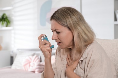 Photo of Woman using inhaler at home. Asthma treatment