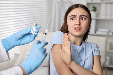 Dental phobia. Dentist with syringe and vial near scared woman in clinic, closeup