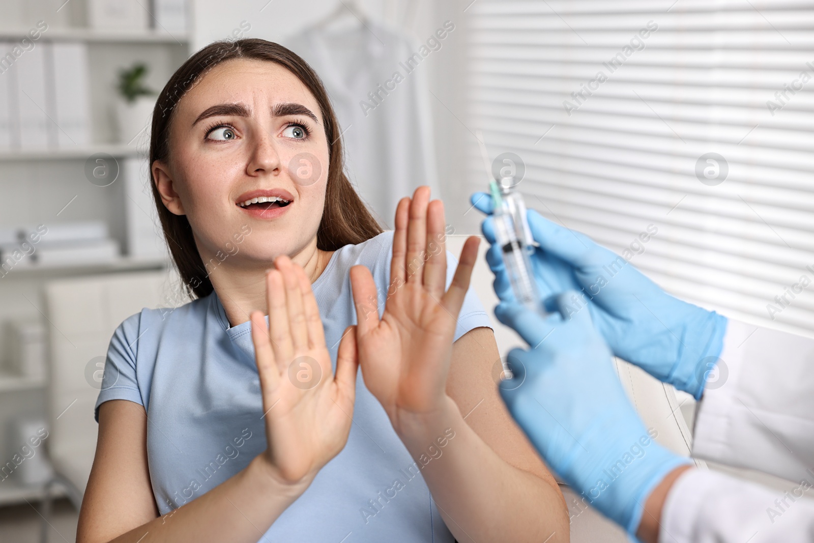 Photo of Dental phobia. Dentist with syringe and vial near scared woman in clinic, closeup