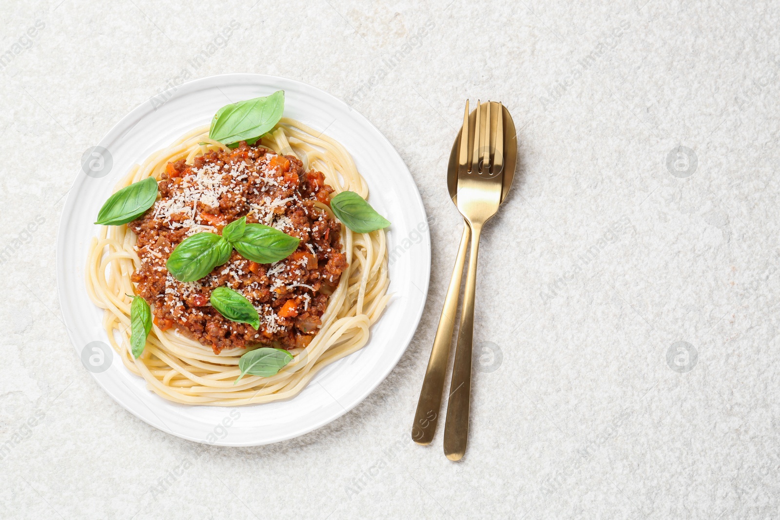 Photo of Delicious pasta bolognese and cutlery on white table, flat lay. Space for text