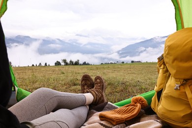 Woman wearing trekking shoes and lying in tent outdoors, closeup