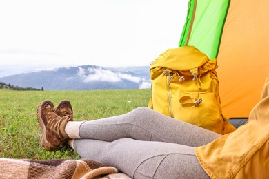 Photo of Woman wearing trekking shoes and lying in tent outdoors, closeup