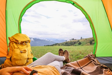 Photo of Woman wearing trekking shoes and lying in tent outdoors, closeup